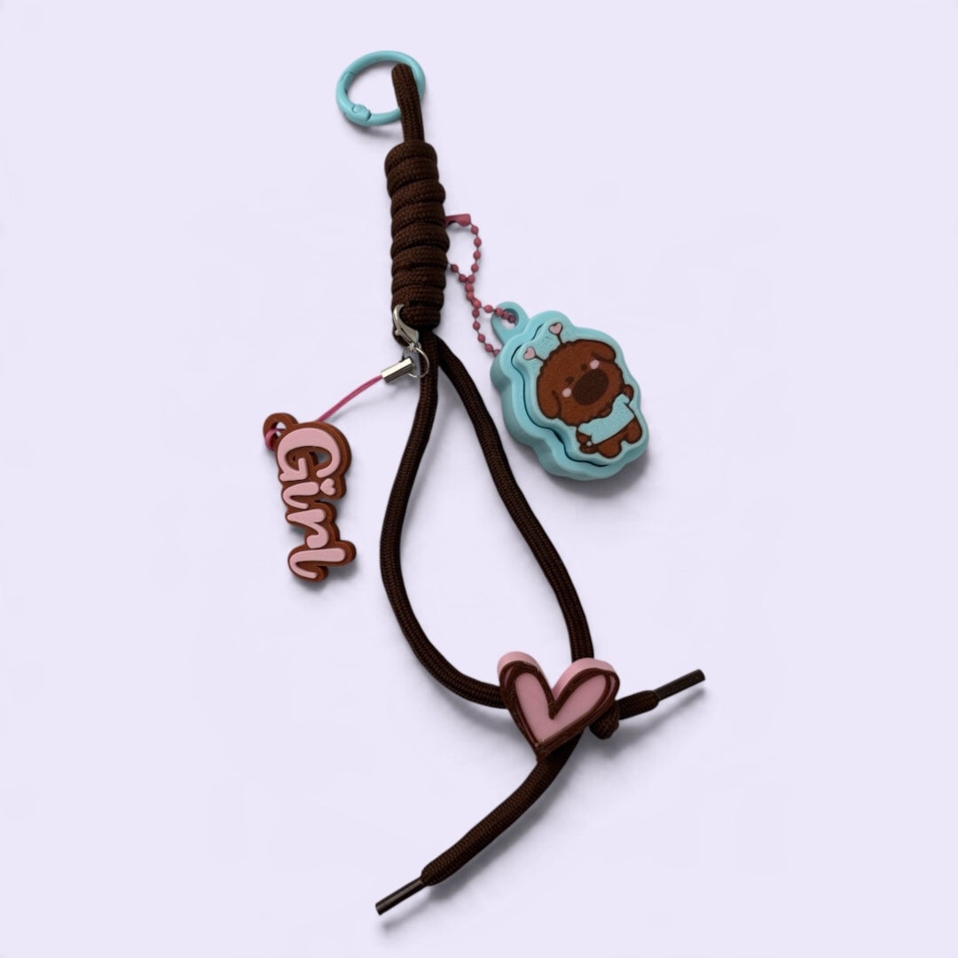 iTsChoCoBu multi-charm keychain with a brown braided cord, blue character charm, Girl script tag, and pink heart.