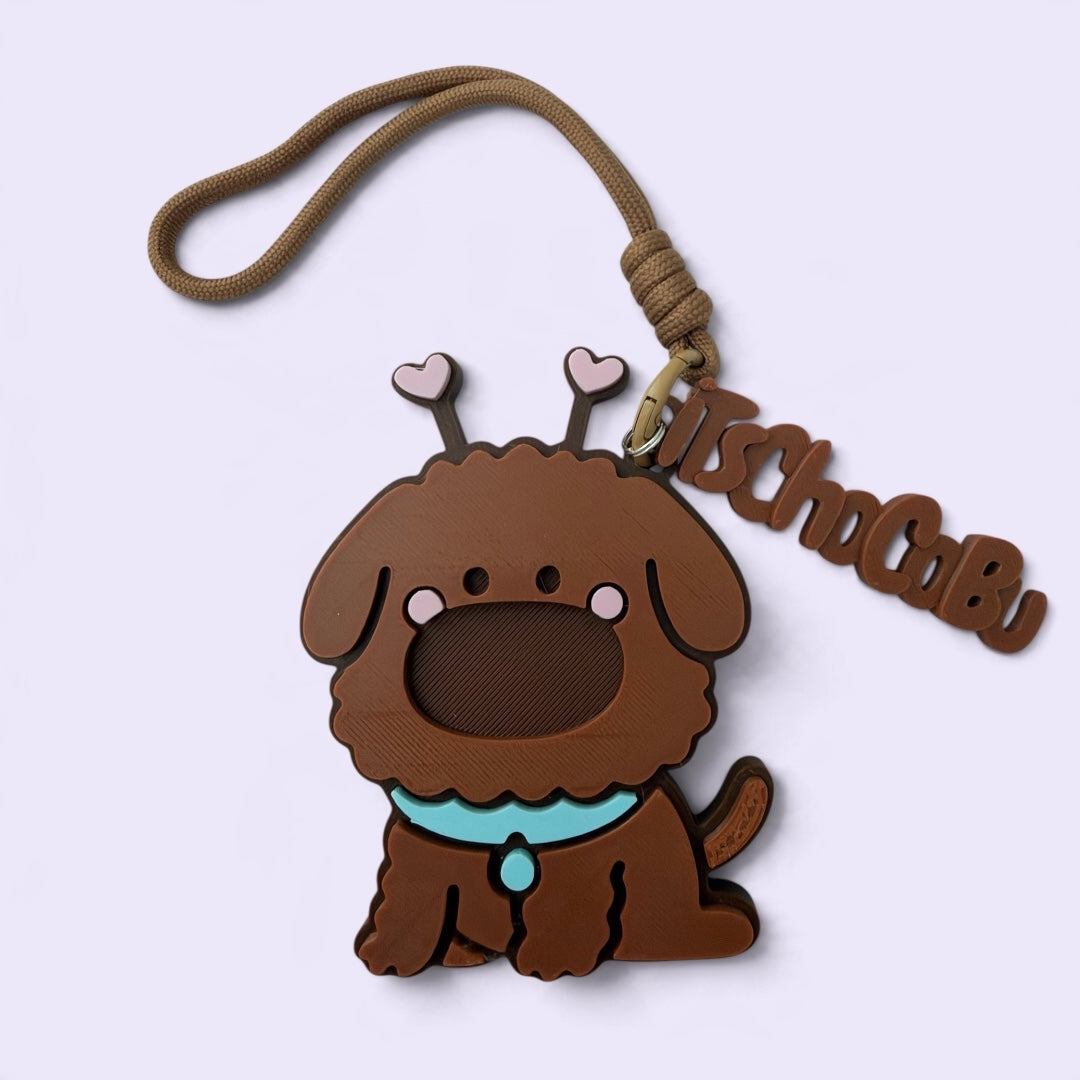 iTsChoCoBu brown silicone puppy keychain with heart antennae, teal collar, and branded charm on a woven cord loop.